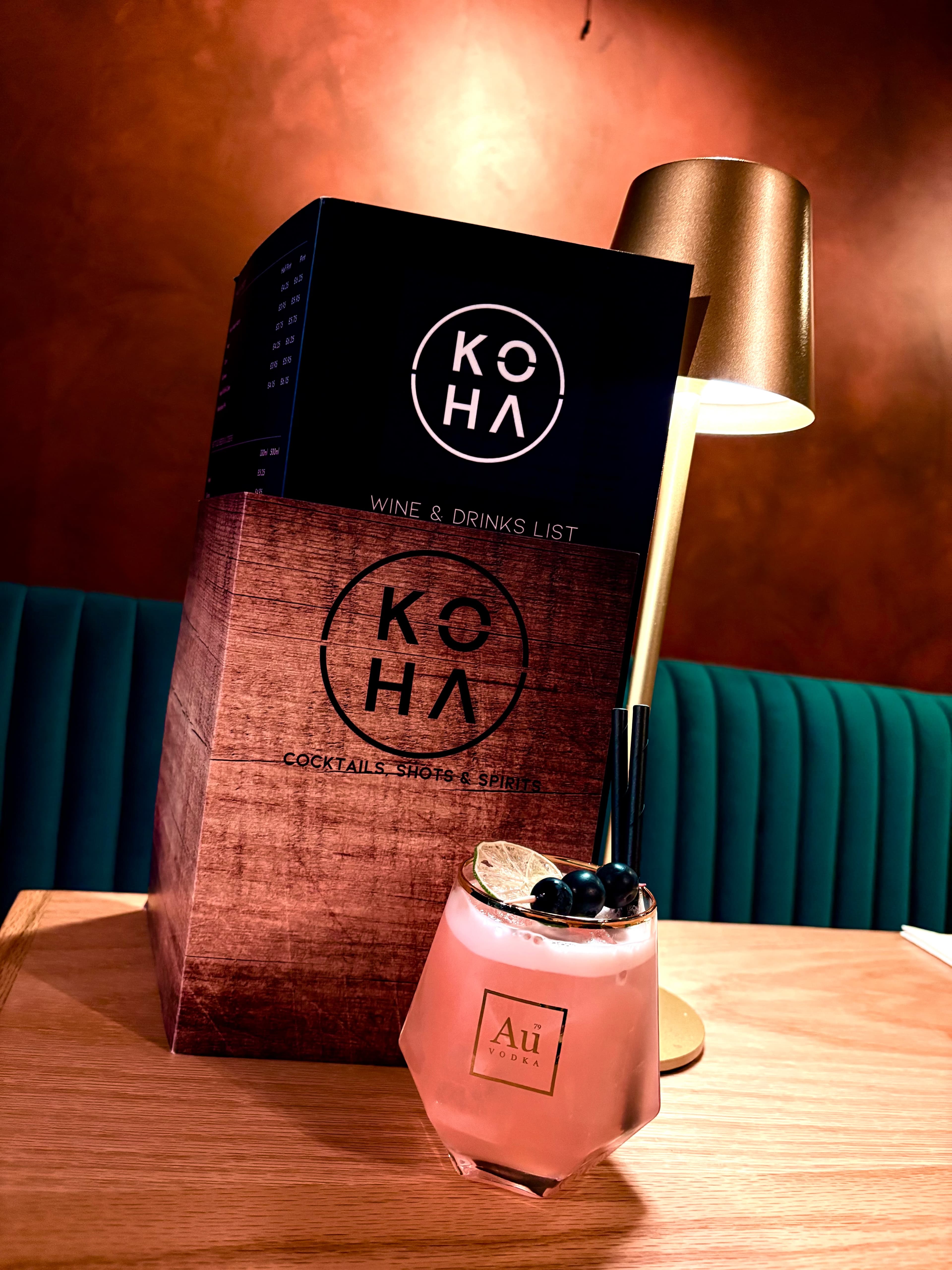 Pink cocktail with blueberry garnish and Koha menu